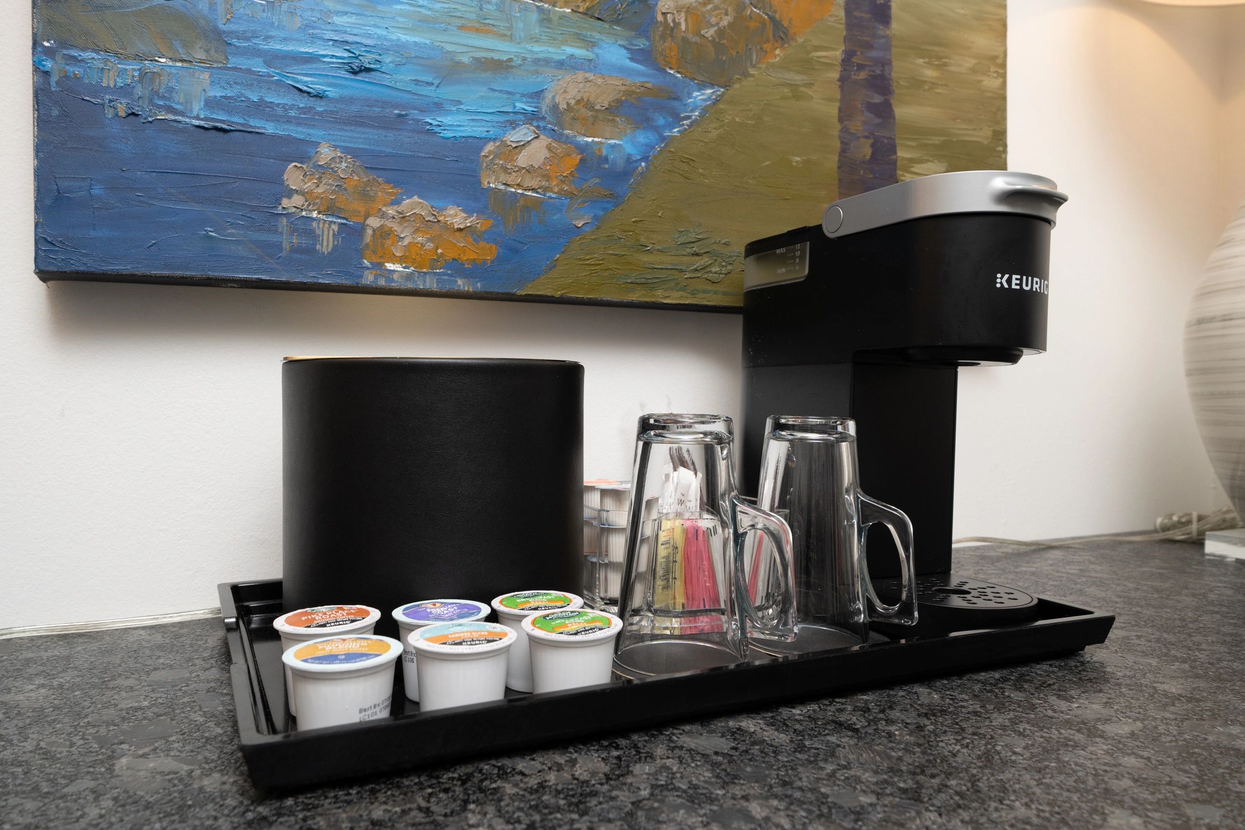 Keurig coffee maker setup with pods and glasses on a tray